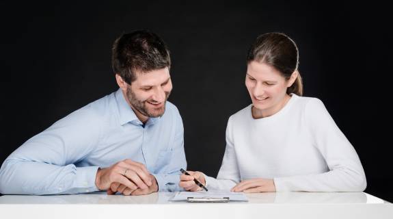 Priv.-Doz. Dr. med. Katharina Lechner und Dr. med. Benjamin Lechner sitzen lächelnd vor einem Tisch und betrachten Unterlagen