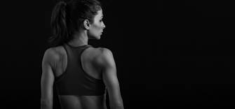 Schwarz-Weiß-Aufnahme einer sportlichen Frau im Sporttop, die mit dem Rücken zur Kamera steht und zur Seite blickt